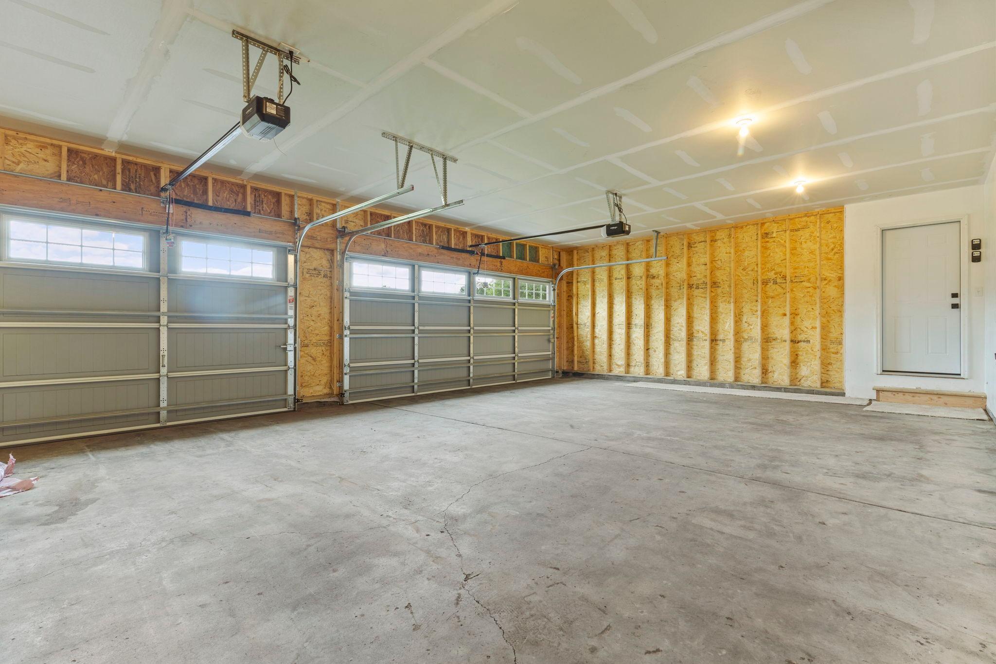 The fully replaced garage features new firewalls, garage doors with windows, and new garage door openers, providing improved safety, functionality, and a refreshed modern look.
