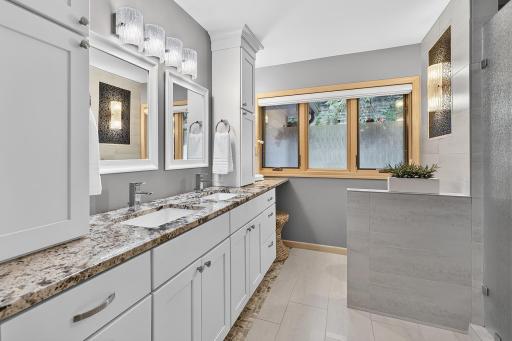 Primary bathshowcases updated cabinetry, double vanities and custom lighting.