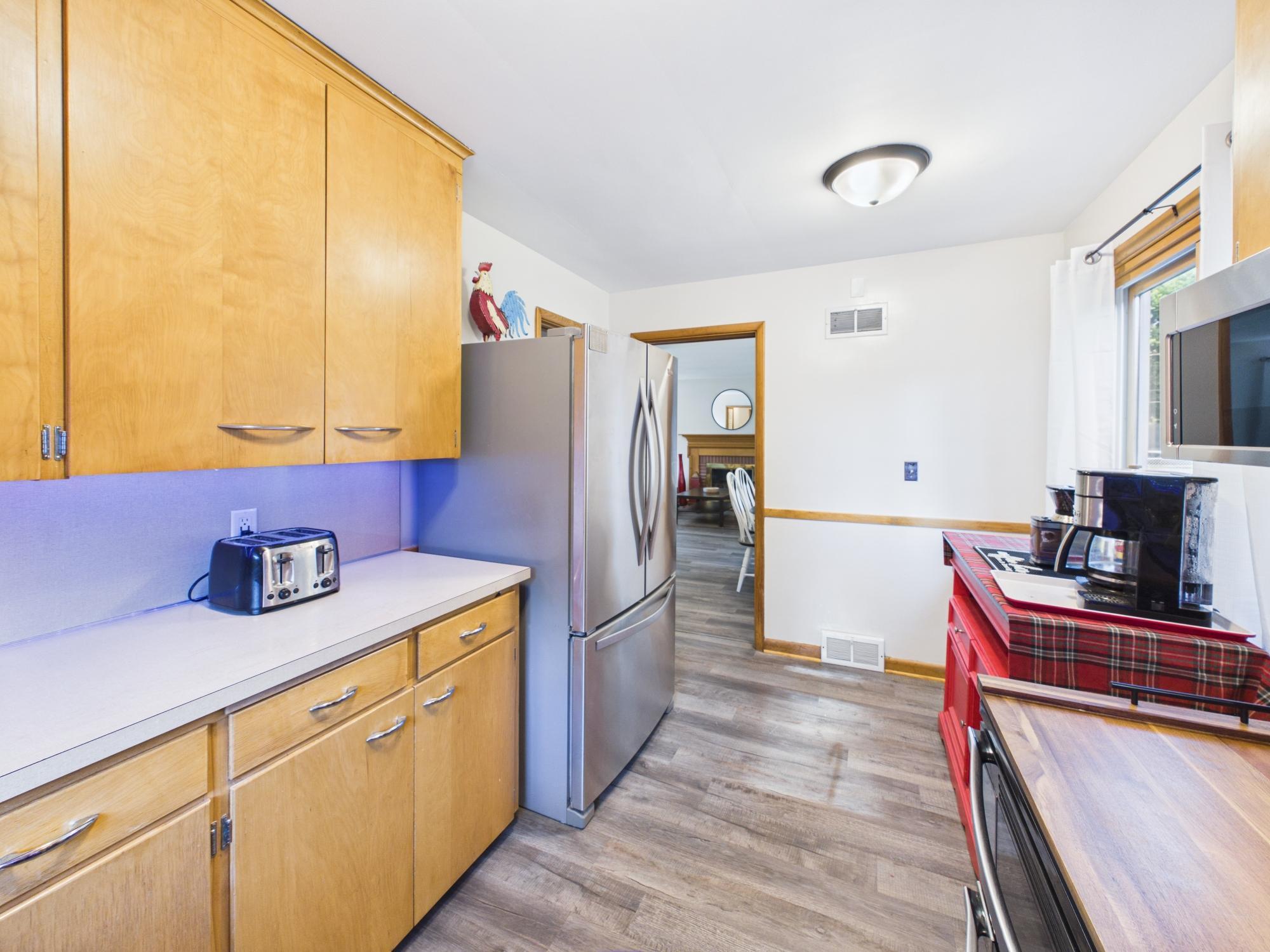 Kitchen view highlighting the cabinetry, counter space, stainless steel refrigerator and connection to the rest of the home.