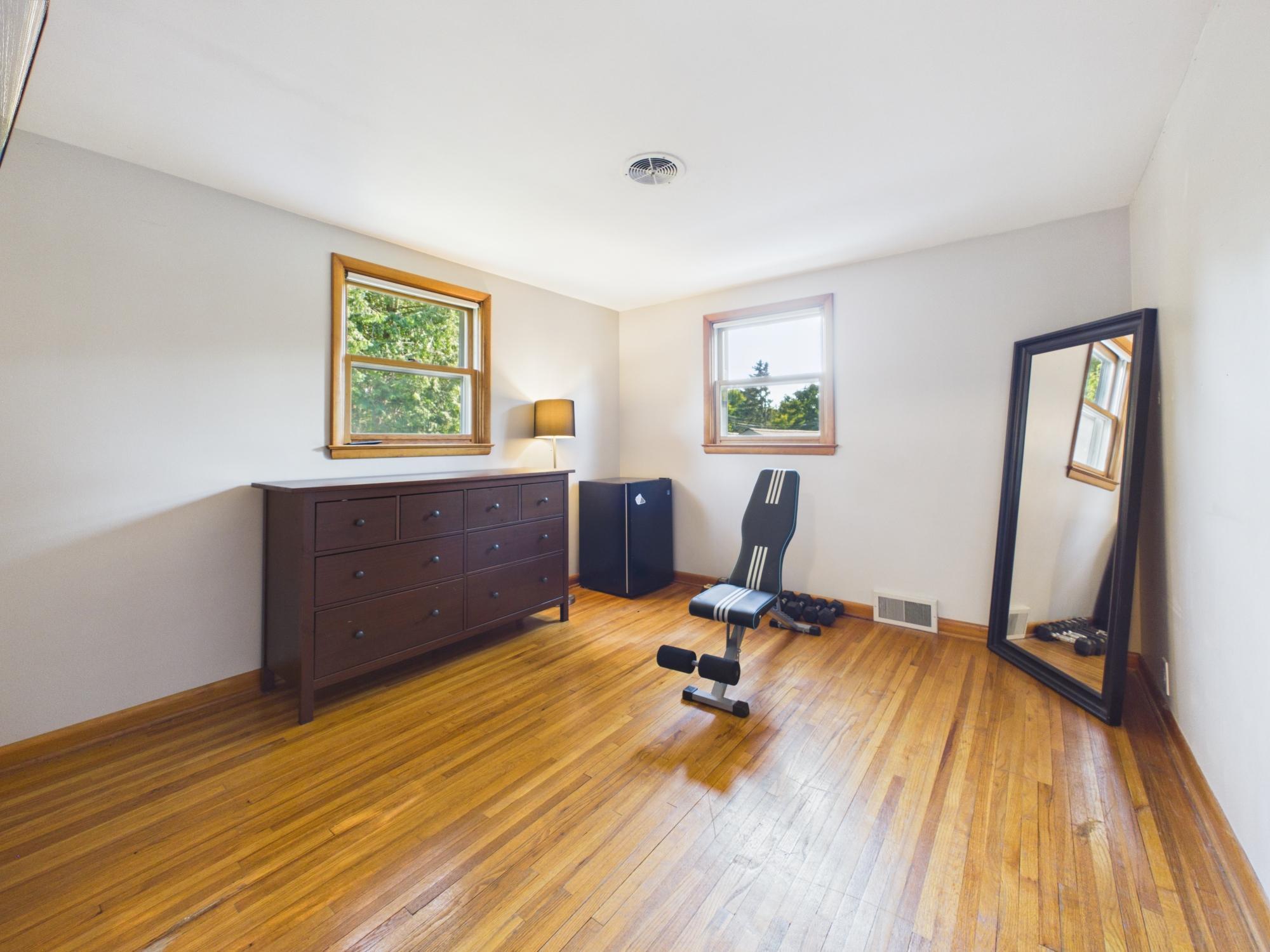 Another view of bedroom 2 featuring hardwood floors and windows on two walls.