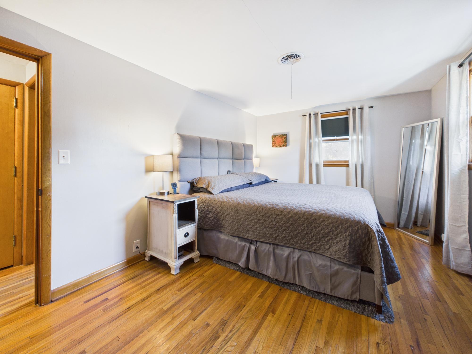 Second view of the primary bedroom highlighting the room's size, hardwood flooring and natural light.