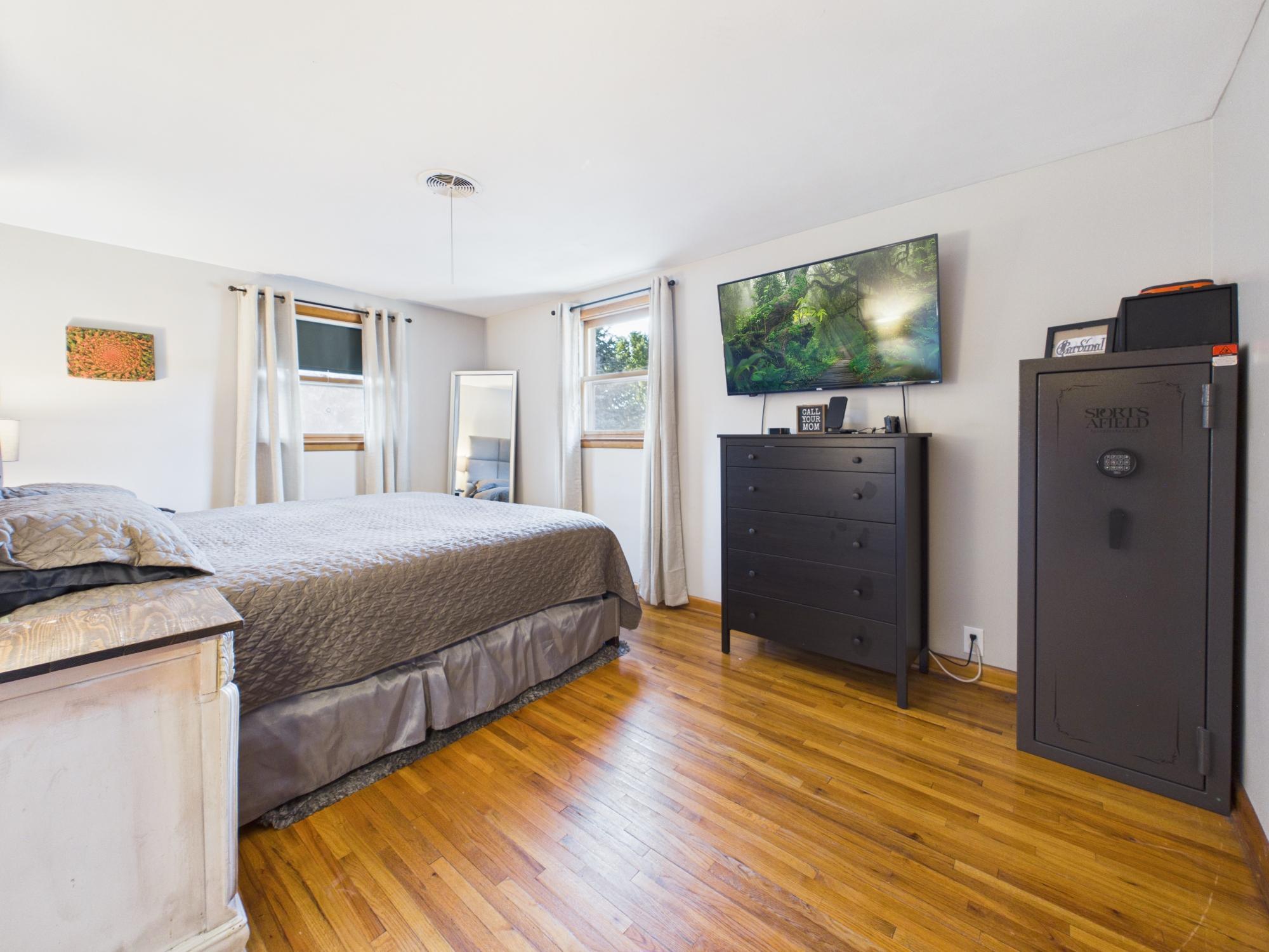 Primary bedroom featuring beautiful hardwood floors, multiple windows and generous space for bedroom furniture.