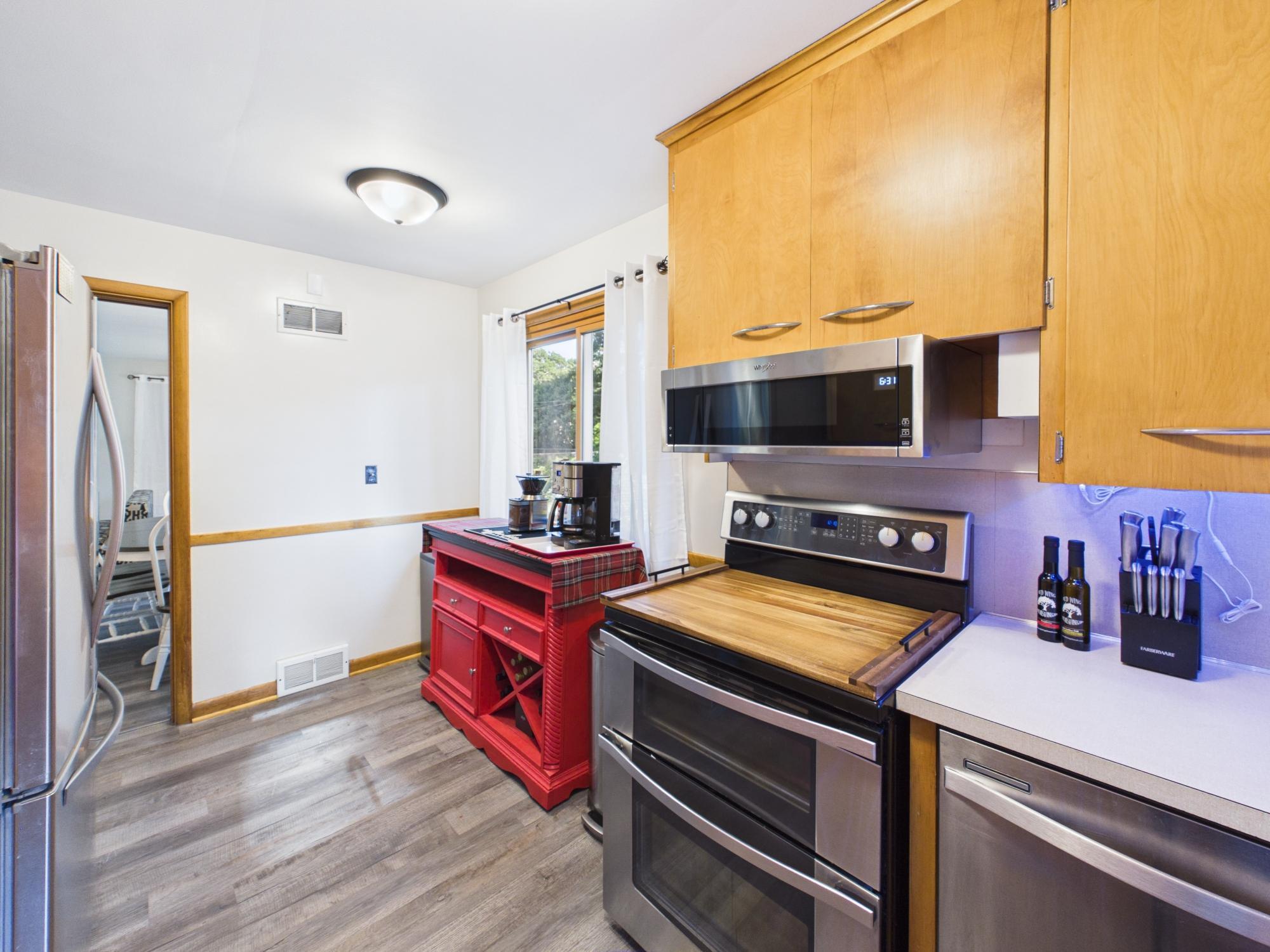 Kitchen cooking area with stainless steel range and microwave, plentiful cabinetry and convenient counter space.