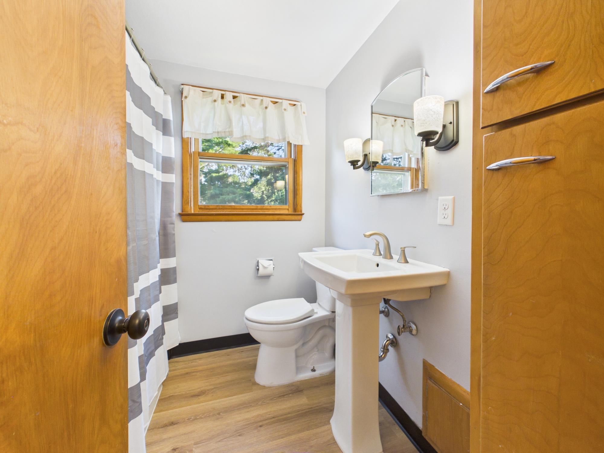 Upper Level bathroom with pedestal sink, natural light and a clean, neutral finish.