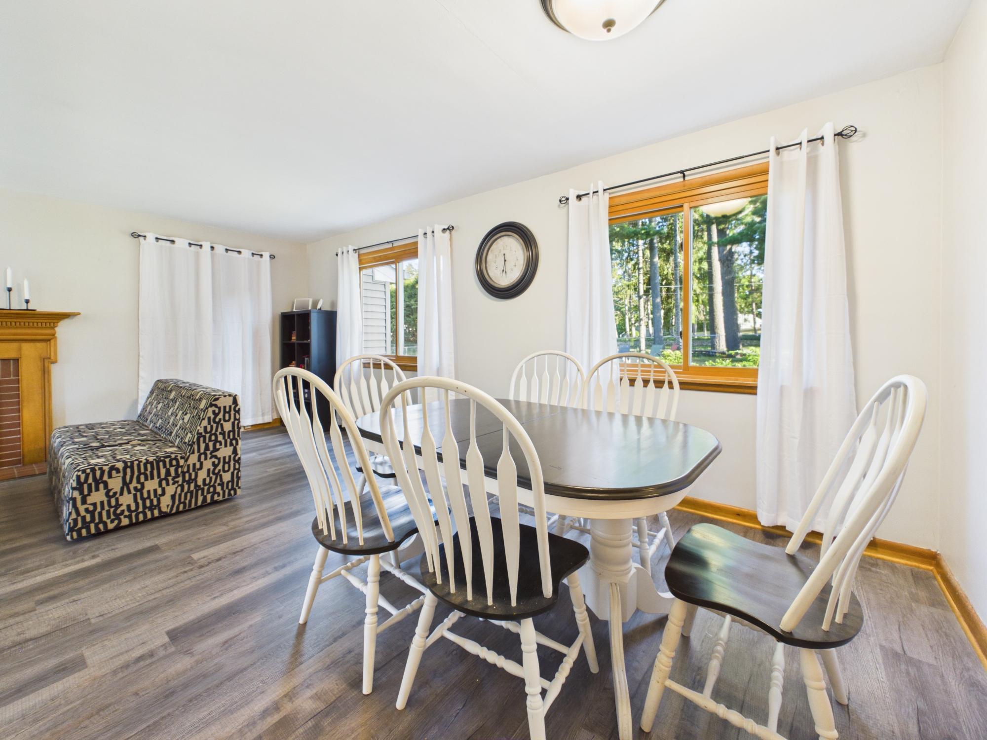Dining area with updated flooring and large windows overlooking the backyard.