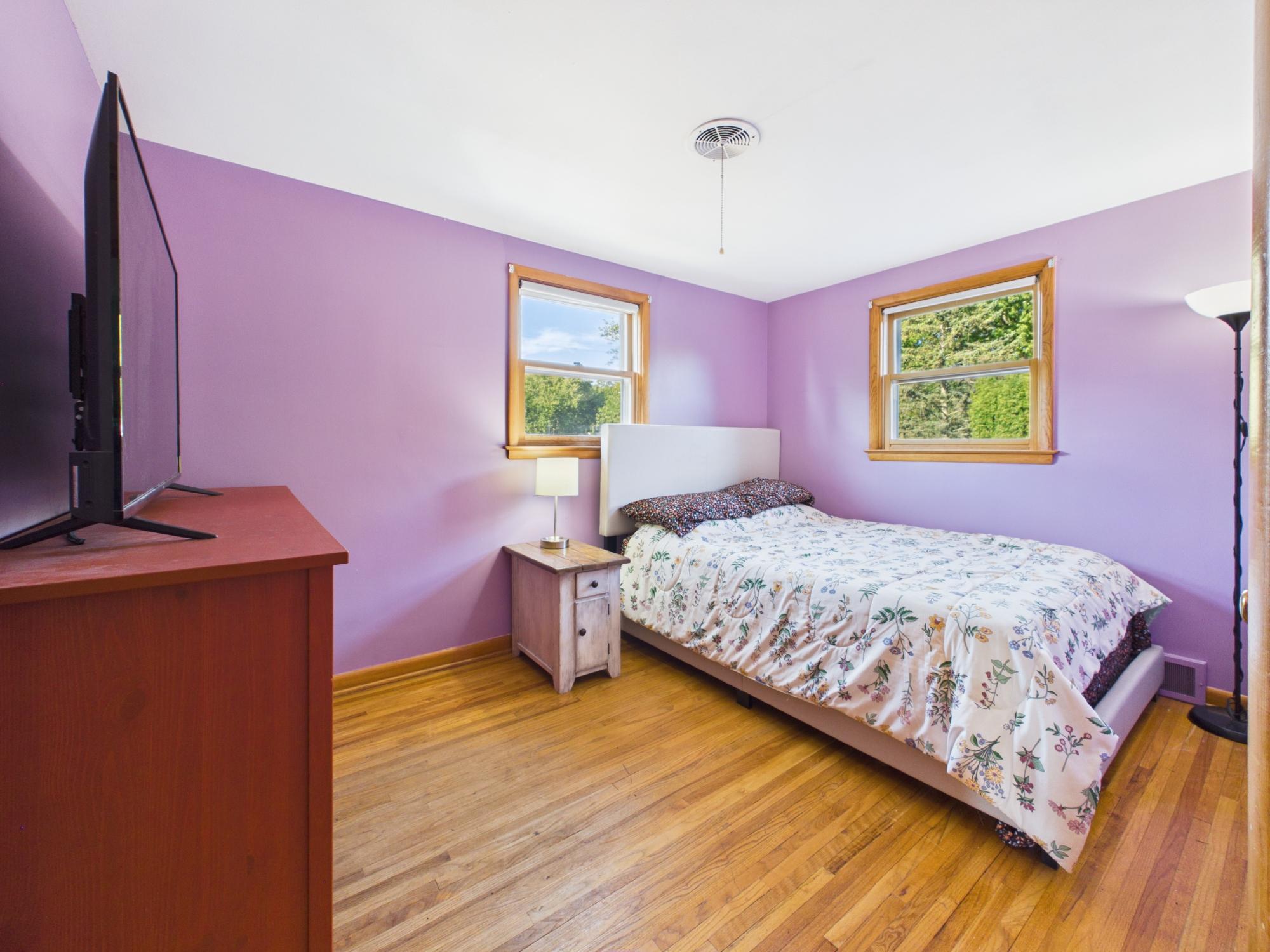 Bedroom 3 with hardwood floors and two windows providing great natural light.