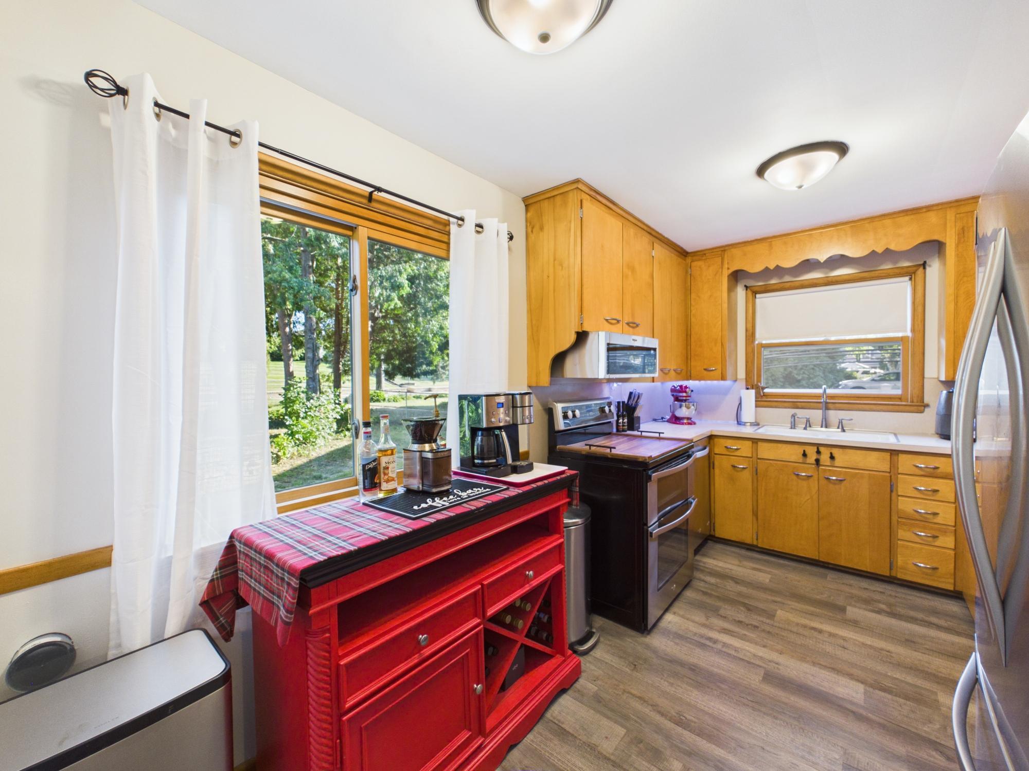 Kitchen with extensive cabinetry, generous workspace and a large window providing natural light and backyard views.