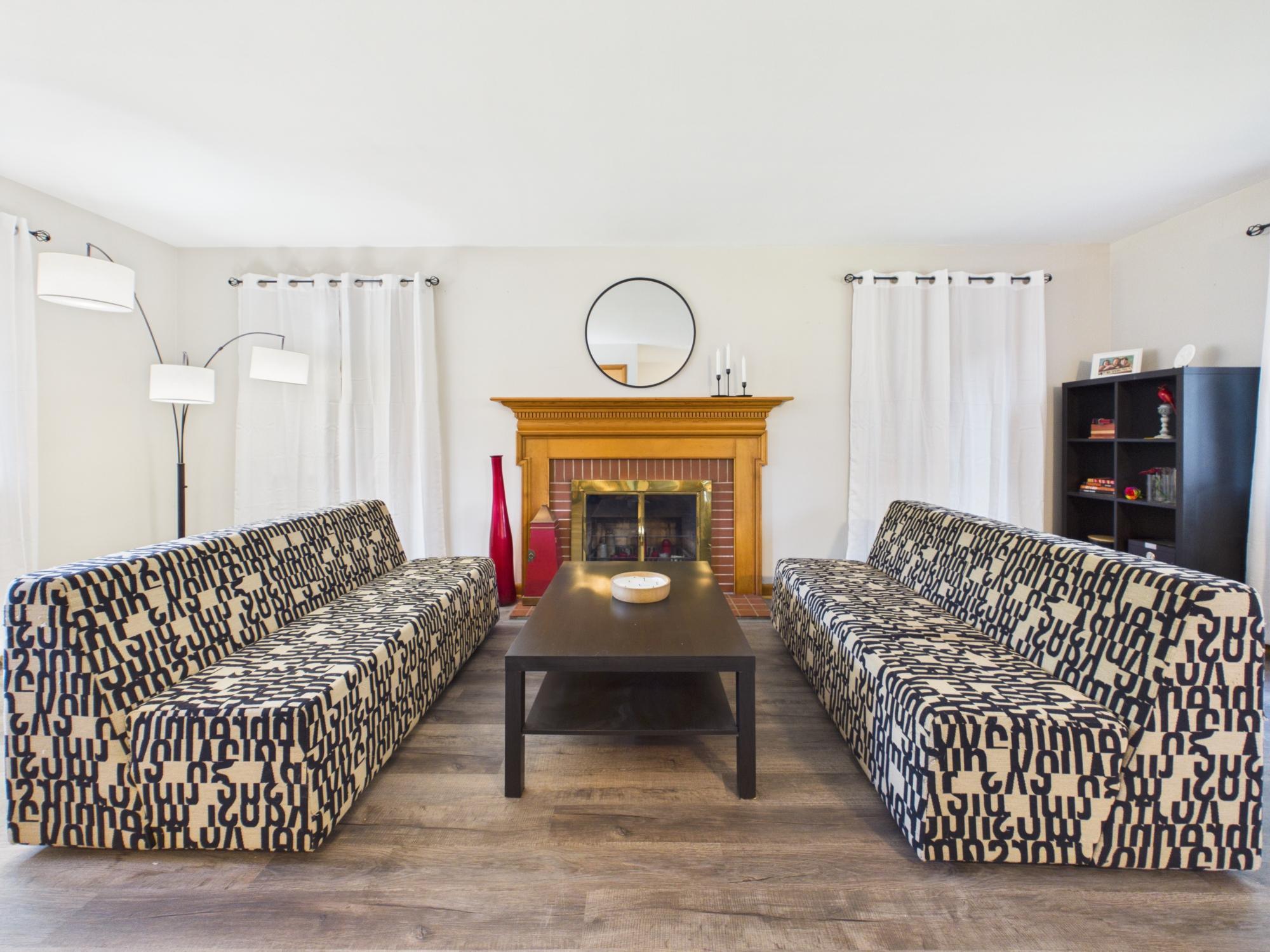 Main living room featuring a wood-burning fireplace, updated flooring and large windows that bring in plenty of natural light.