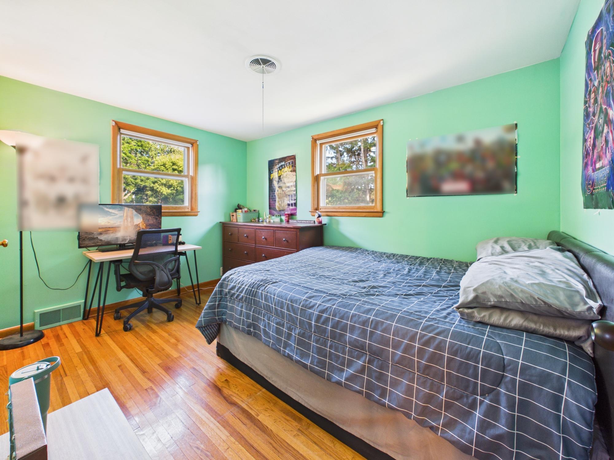 Bedroom 4 featuring hardwood floors, two windows and enough space for both sleeping and desk areas.