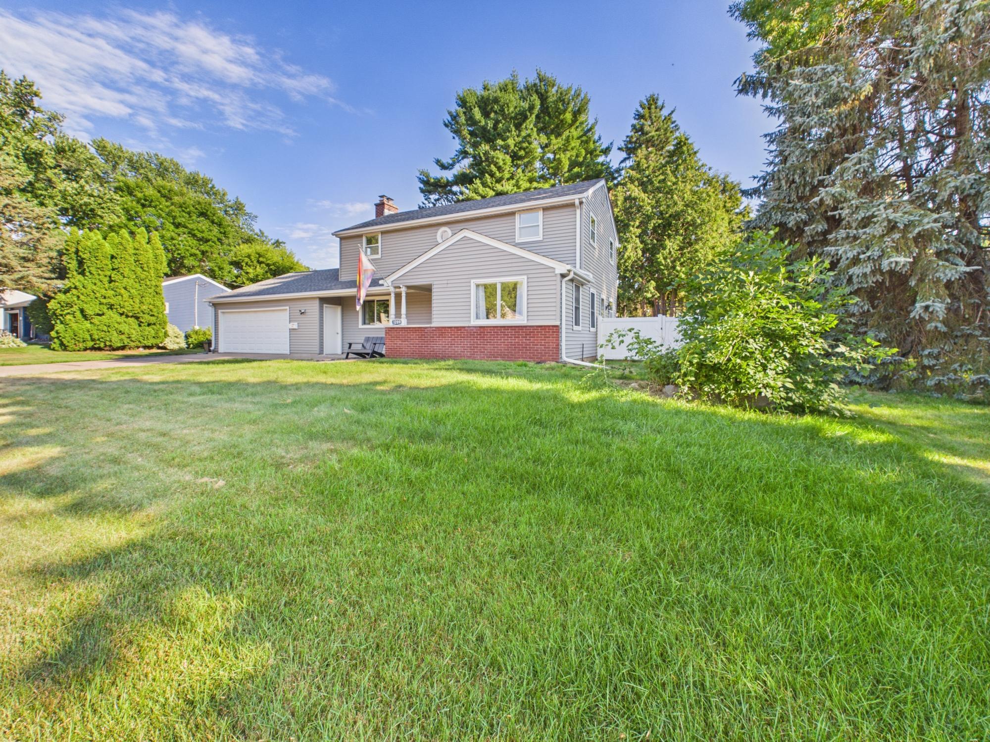 Final exterior view showcasing the home from the lawn and the spacious corner of the property framed by mature trees.