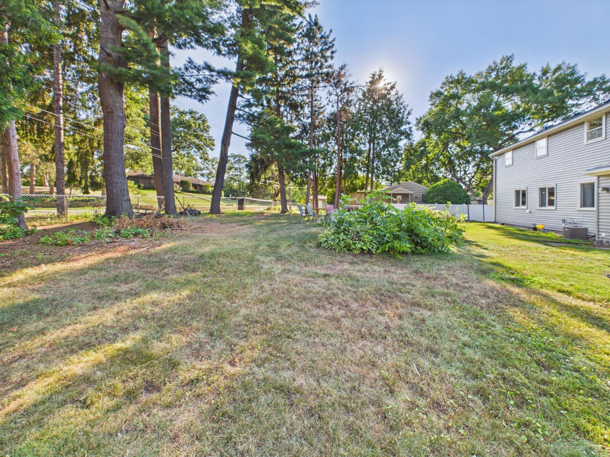 Backyard view showing the combination of mature shade trees, open lawn and established landscaping.
