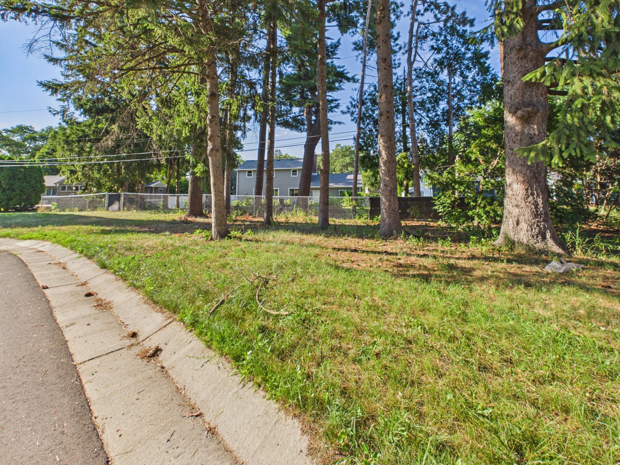 View along the rear portion of the property highlighting mature trees and the fenced backyard.
