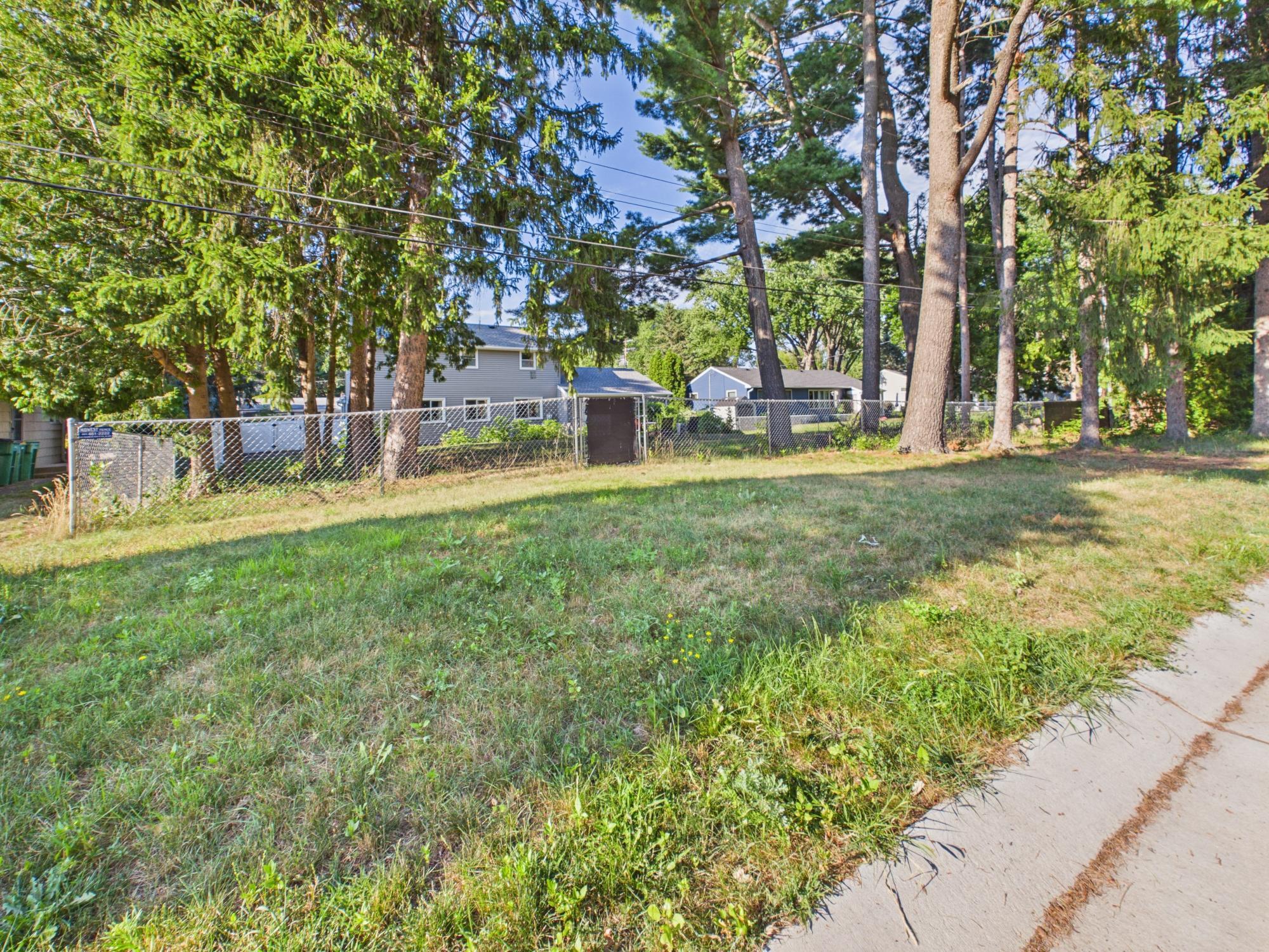 Wide view along the fenced yard showcasing the property's mature trees and generous outdoor space.