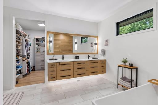 Spa-inspired primary bath featuring a floating dual-sink vanity, designer lighting, and a spacious walk-in closet.