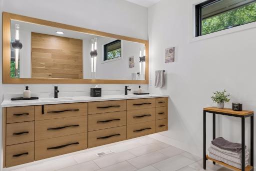 Spa-inspired primary bath featuring a floating dual-sink vanity, quartz countertops, designer lighting, and a spacious walk-in closet.