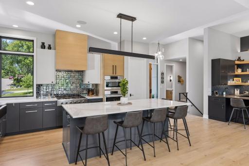 Kitchen highlights include stainless steel appliances, large enter island with seating, and ample cabinet and counter space.