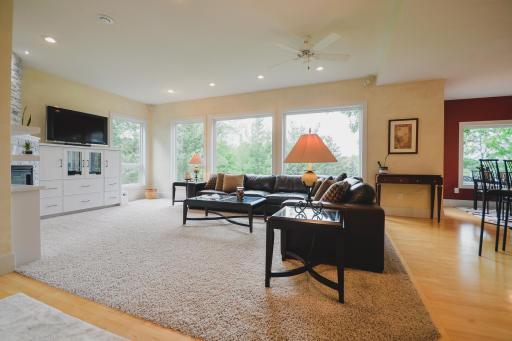 The living room showcases beautiful windows overlooking the park-like setting