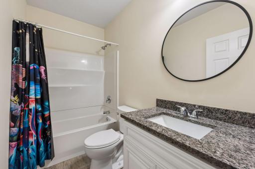 A nearby full bathroom features a granite vanity, modern finishes, and a tub/shower combination for added convenience.