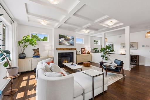 Relax in the inviting living room featuring elegant coffered ceilings, abundant natural light, and a cozy gas fireplace that serves as the perfect focal point for everyday comfort.
