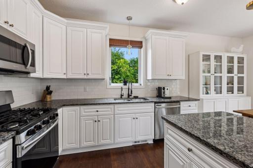 Beautiful white cabinetry, granite countertops, subway tile backsplash, and a large picture window create a bright, functional kitchen with timeless appeal and generous prep space for every meal.