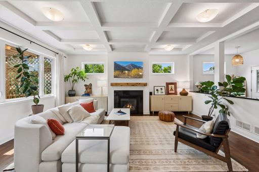 The spacious living room offers a warm and welcoming atmosphere with oversized windows, beautiful architectural details, and plenty of room for entertaining or relaxing beside the fireplace.