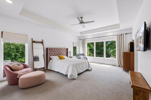 Escape to the spacious primary suite featuring oversized windows, soaring ceilings, and plenty of room for a sitting area. Natural light pours in, creating a peaceful retreat.