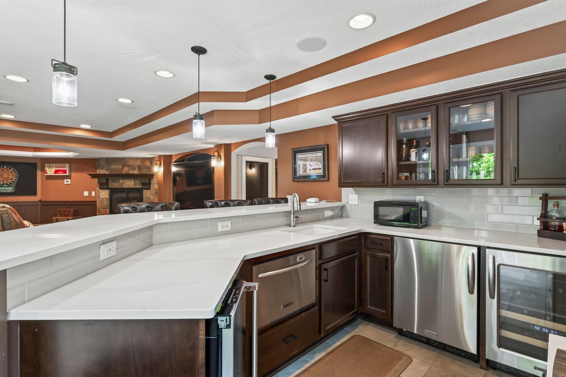 The lower level is built for entertaining with a stunning bar featuring quartz countertops, an ice maker, microwave, dishwasher, beverage and wine refrigerator.