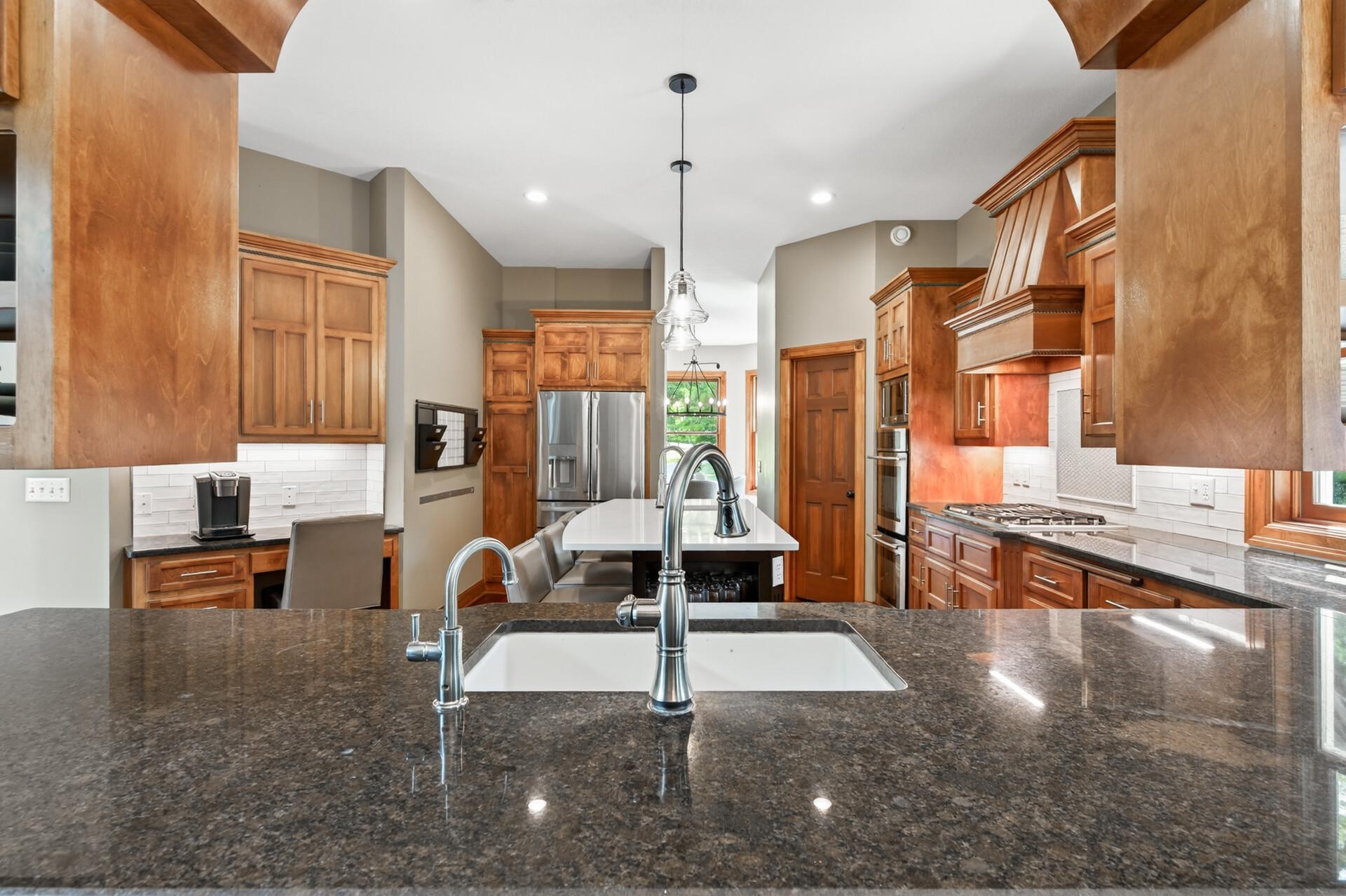 A beautifully updated kitchen featuring stone countertops, custom wood range hood, and gorgeous new cabinetry.