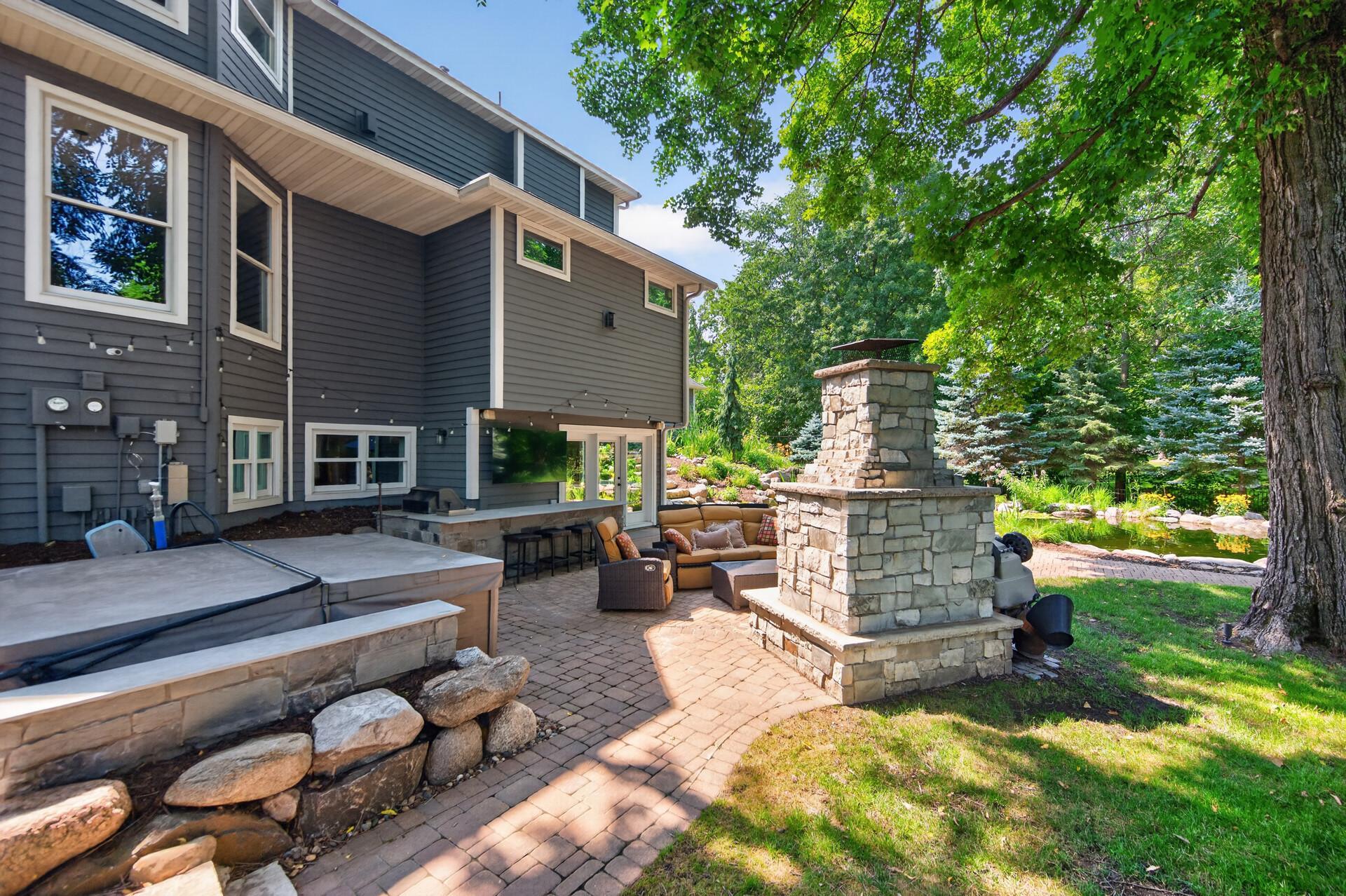 Continue the party outdoors at the covered bar complete with concrete countertops, a stone fireplace, and an oversized TV - perfect for game day.
