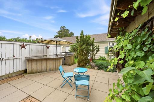 The private patio/cabana has a built in grill area and is surrounded by green space and established plantings—ideal for relaxing or entertaining.