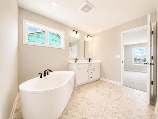 (Photo is of the actual home.) Dual sinks, a glass-enclosed shower and a separate soaking tub contribute to the spa-like atmosphere of the en-suite bathroom