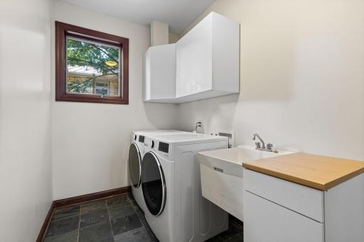 Main level tiled laundry room with utility sink and additional storage.