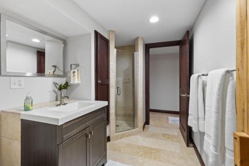 Lower level bath with walk in shower and hallway leading to bedroom.