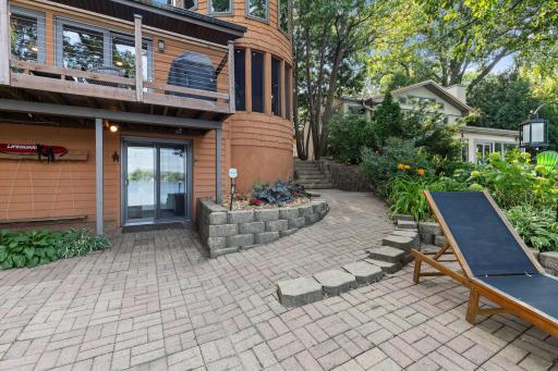 The outdoor area is easily accessible from either the side-entry enclosed porch or the lower level of the home, providing convenient access to the patio and waterfront.