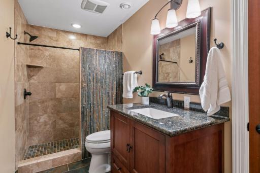 Gorgeous newer 3/4 bathroom in the lower level offers a new vanity with granite countertops, heated tiled flooring and wonderful tiled walk-in shower with a beautiful accent wall. There is also a linen closet within too.