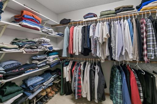 Large walk-in closet in the primary suite with lots of hanging space and shelves for folding clothes.