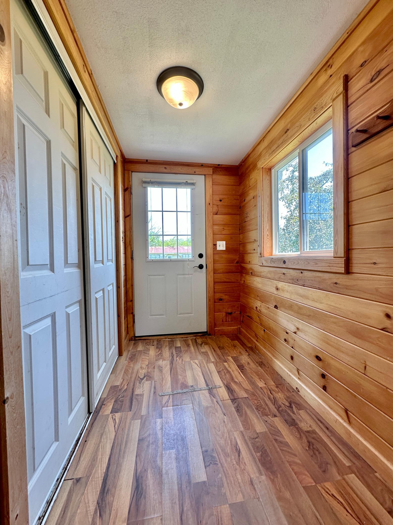 The back entry of the home is finished with tongue and groove siding, a wood like vinyl floor and a large coat closet.