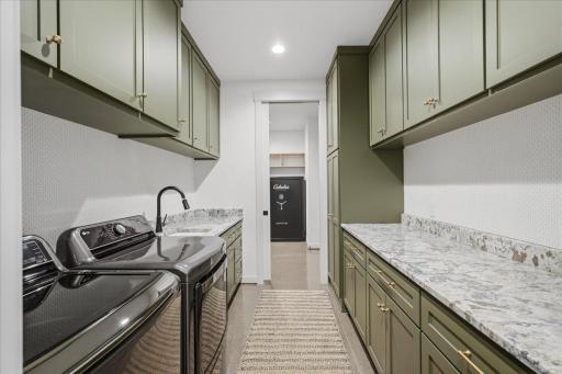 Laundry room features a sink, counter space for folding and ample storage!