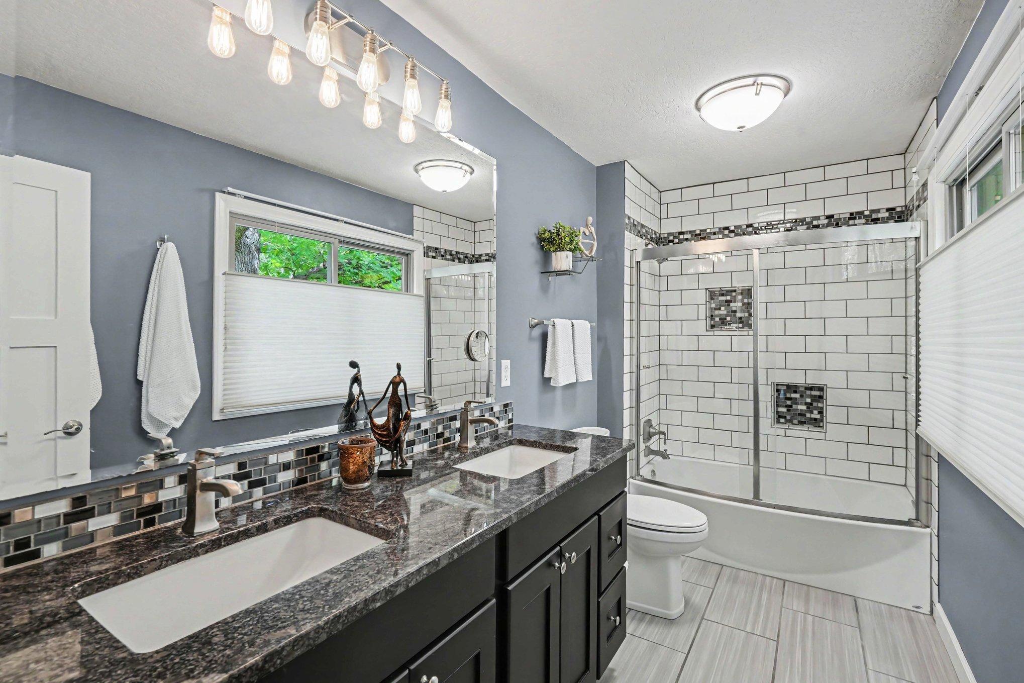 The private primary bathroom has tile flooring, tile backsplash, two sinks and a shower/tub combo.
