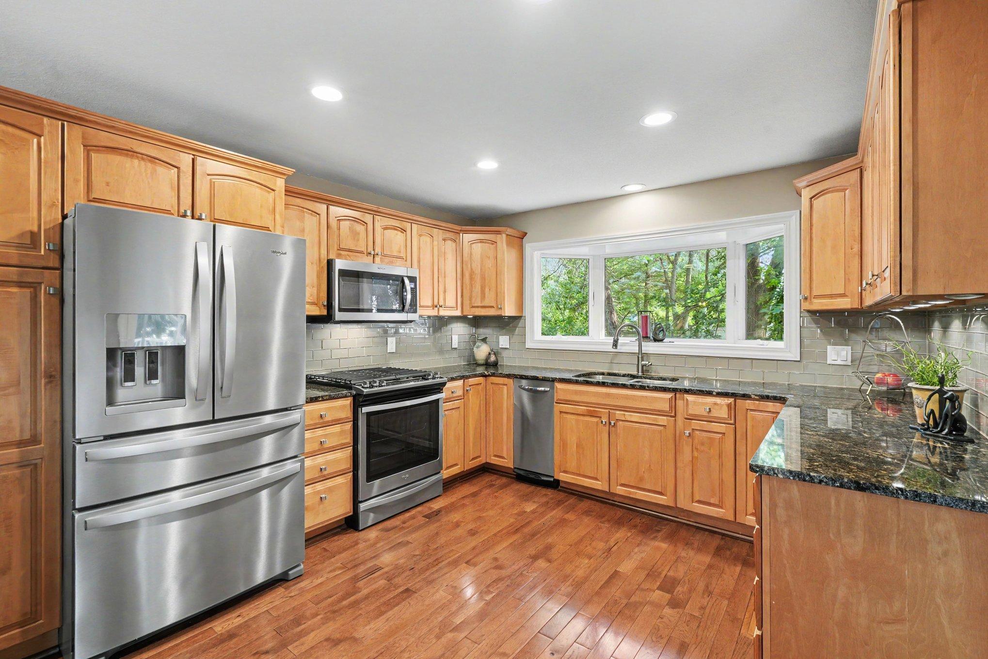 The kitchen boasts stainless steel appliances including a trash compactor, tile backsplash and ample cabinets.