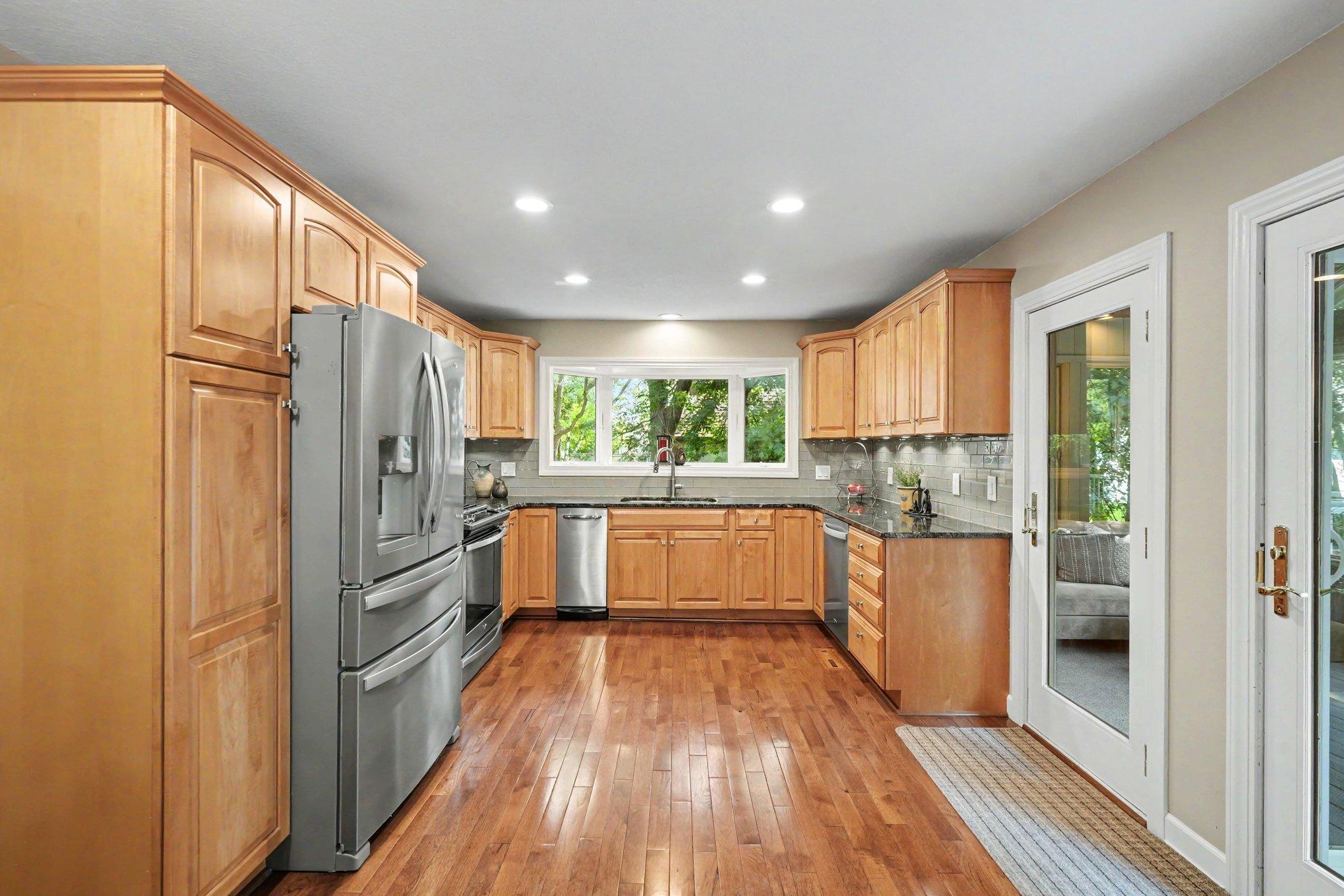 New triple window above the kitchen sink with views of the side yard and mature trees