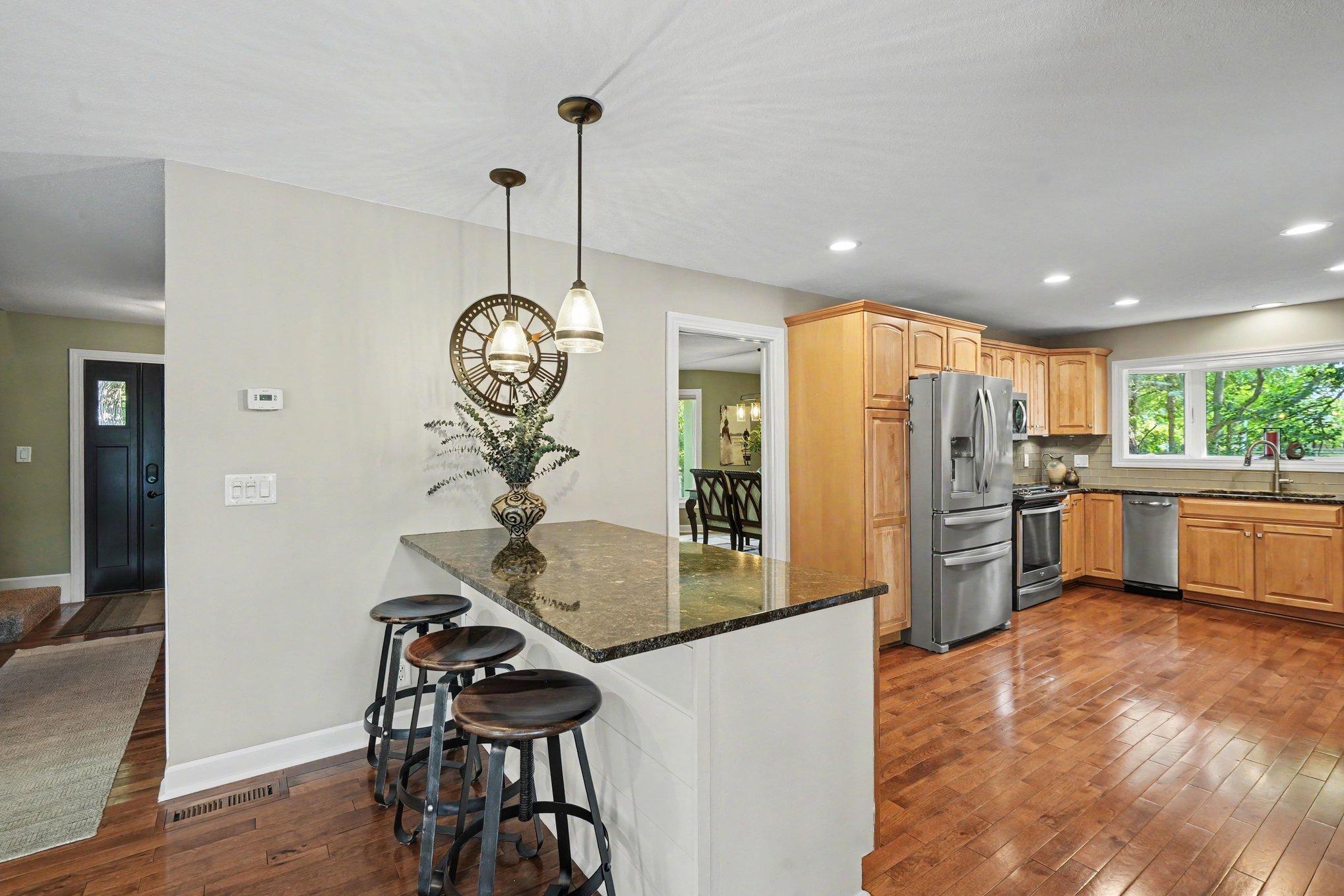 View from the informal dining area towards the foyer, front door, kitchen and island seating.