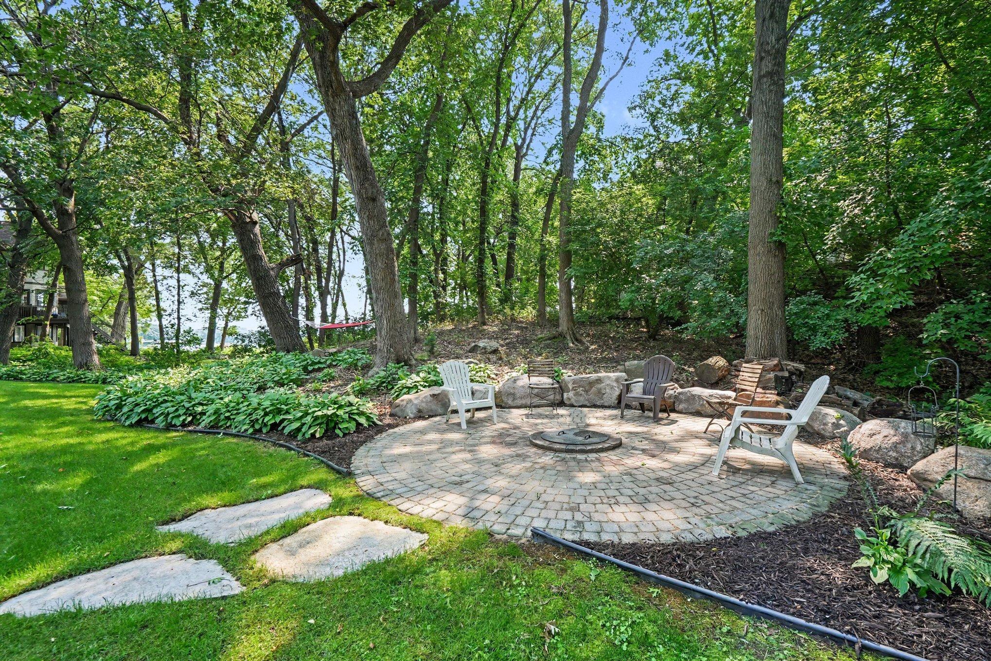 Beautifully landscaped backyard with la circular paver patio with a built-in firepit.