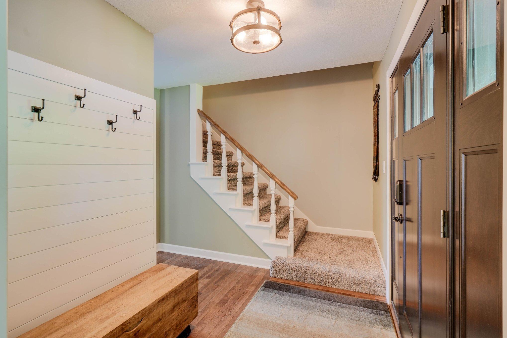 The foyer has a new front door, hooks for coats and stairway to the upper level.