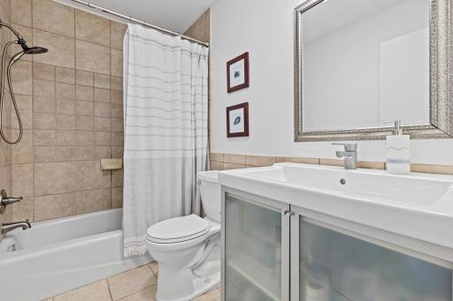 Tucked near the bedrooms, this well-kept bathroom offers everyday comfort with a frosted-glass vanity and timeless tile detailing.