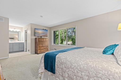 The spacious primary suite offers a private ensuite bath just steps away, with treetop views filtering through the window.