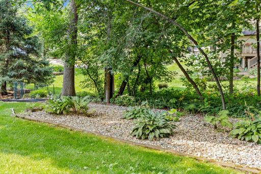 A sprawling, tree-canopied green space stretches out behind the home, offering room to garden, play, or simply enjoy the outdoors.