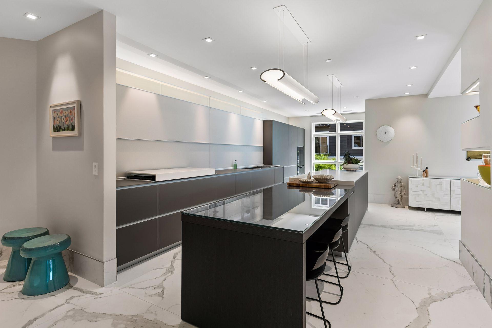 The kitchen takes center stage with sophisticated Valcucine cabinetry, a generous island with seating, and a sleek, minimalist aesthetic that feels effortlessly luxurious.