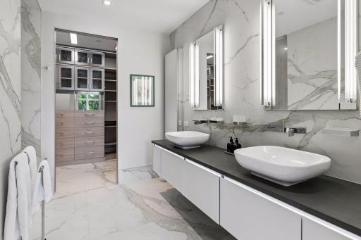 Primary bathroom features double sinks, porcelain flooring and walls, walk in shower, and walk-in closet