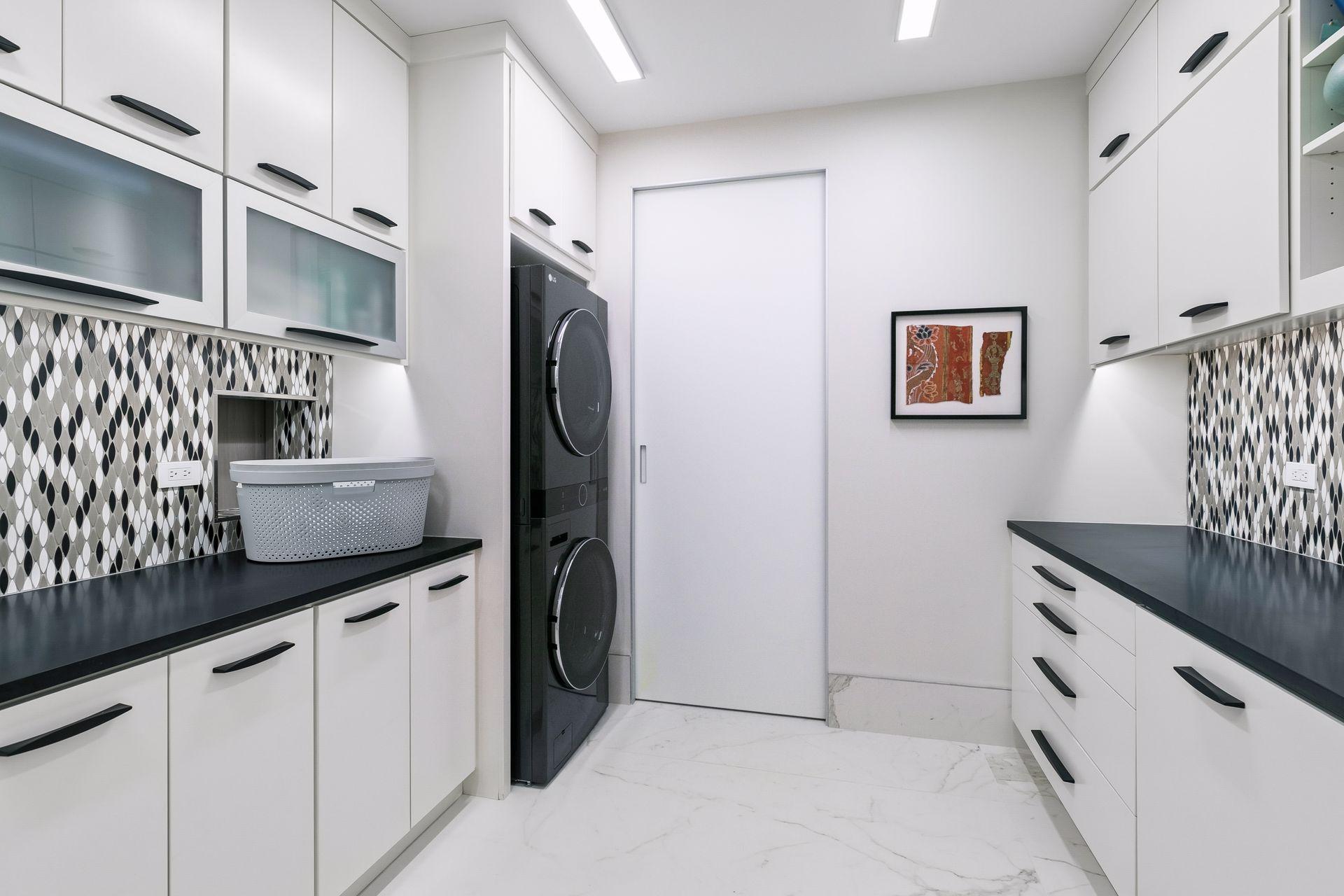This spacious laundry room offers abundant cabinetry, generous counter space, and a dedicated storage room just beyond